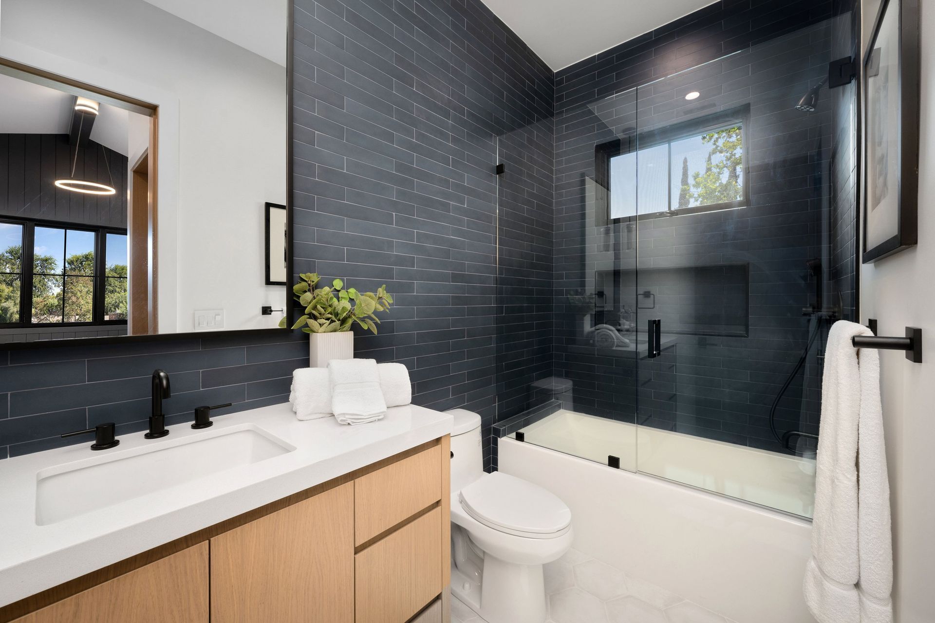 Bright marble bathroom with double vanity, large mirror, glass shower, and chandelier lighting
