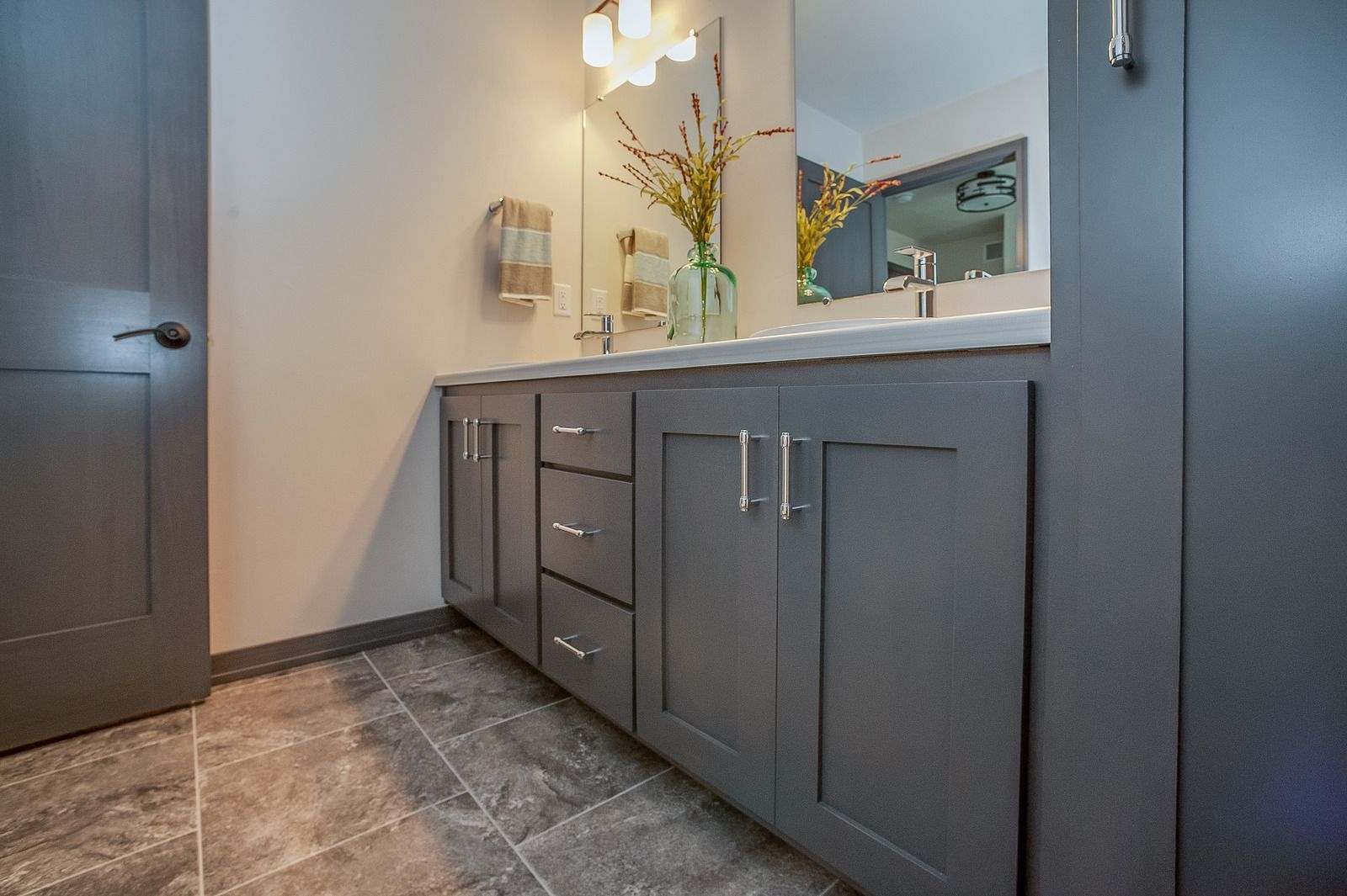 Modern bathroom vanity with dark cabinets, gray countertop, mirror, and tiled floor