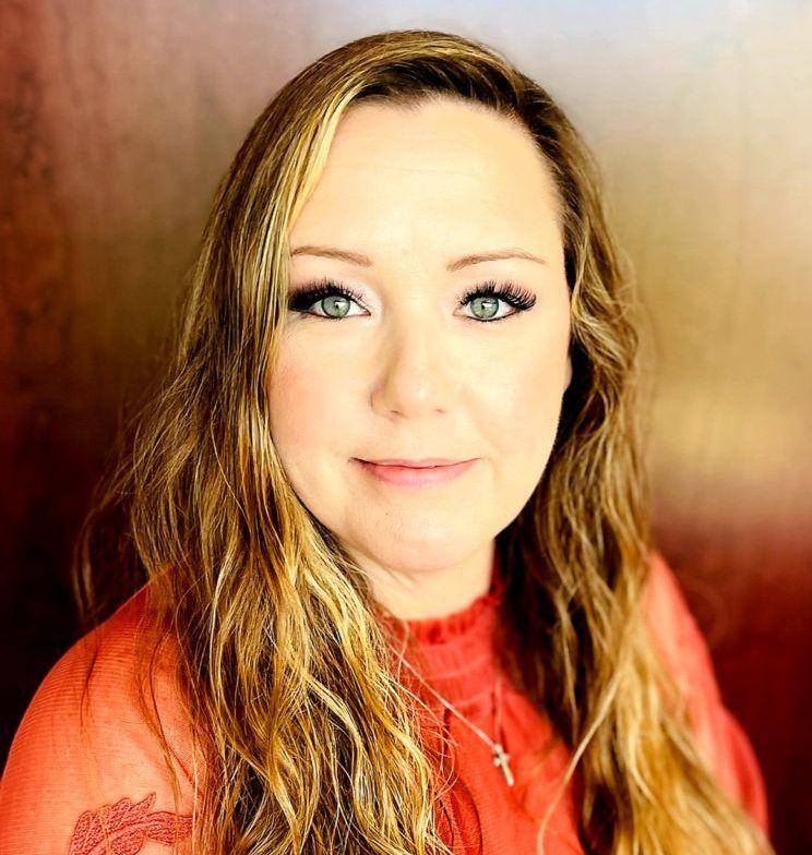 Portrait of a woman in a red sweater with long wavy hair against a wooden background