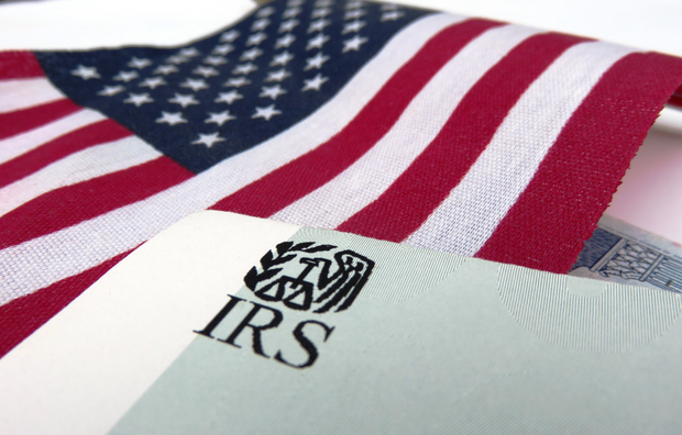 U.S. flag draped over an IRS tax form with the IRS logo visible