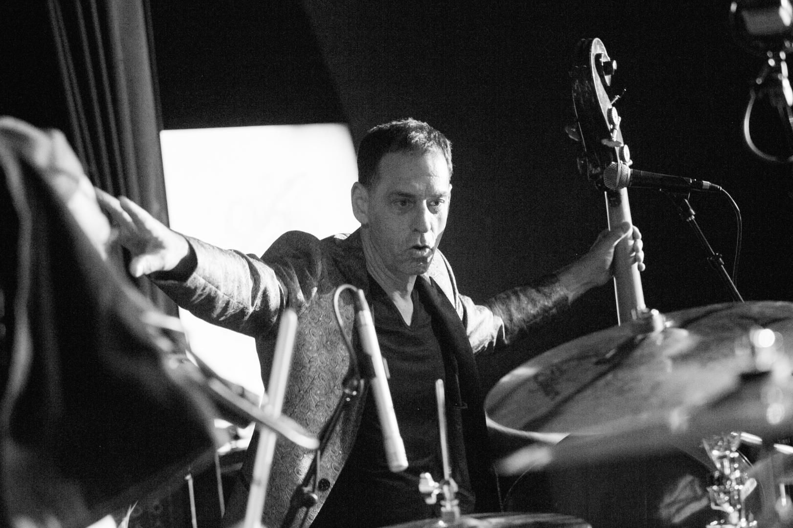 A man is playing drums in a black and white photo.