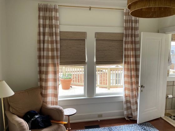 Living room with plaid curtains, window blinds, armchair, and open door to a balcony