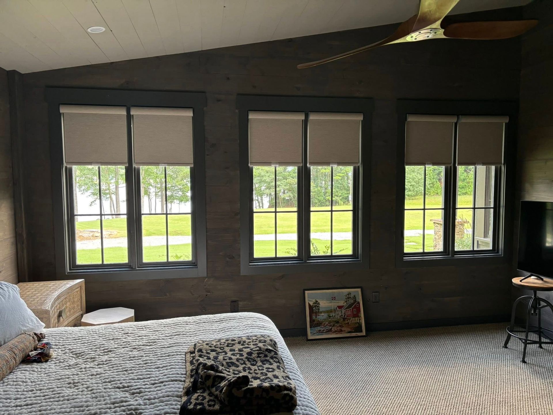 Spacious bedroom with multiple windows, a bed, patterned carpet, and a ceiling fan