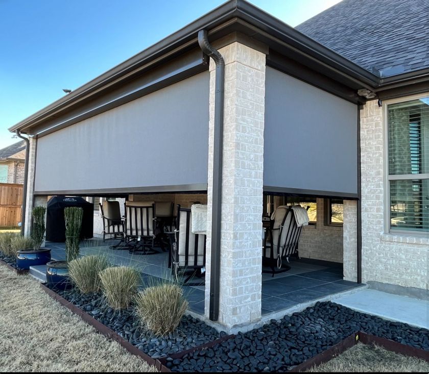 House patio with outdoor furniture and a gray retractable screen enclosure under the roofline