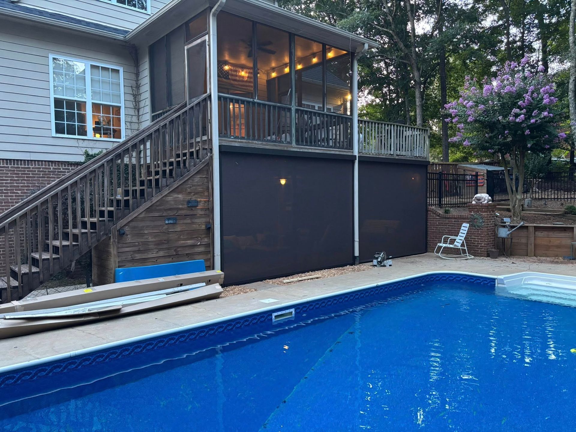 Backyard pool with a raised deck and screened enclosure beside a house