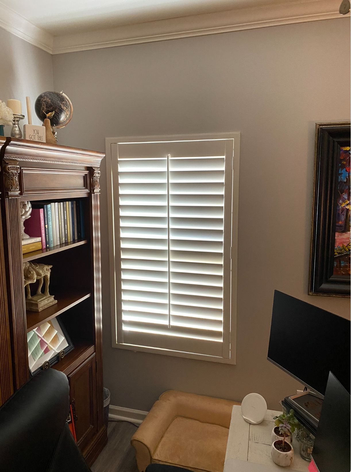 Home office corner with bookshelf, shuttered window, desk, and monitor