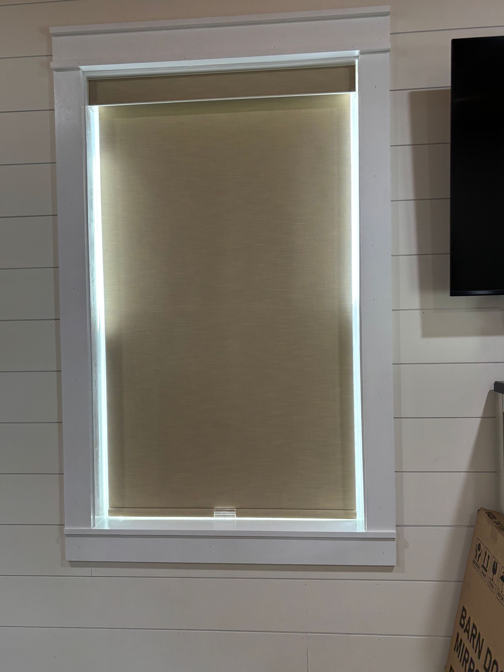 Window with a beige roller blind partially closed, set in a white tiled wall.