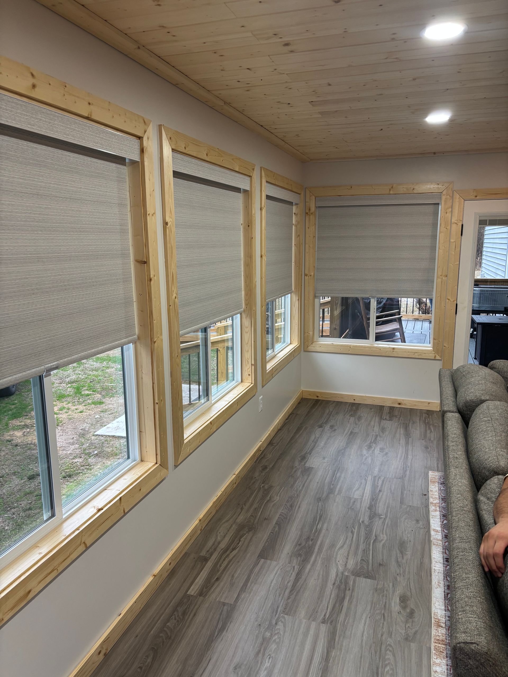 Sunroom with wood ceiling, large windows, gray floor, and couch along the right wall