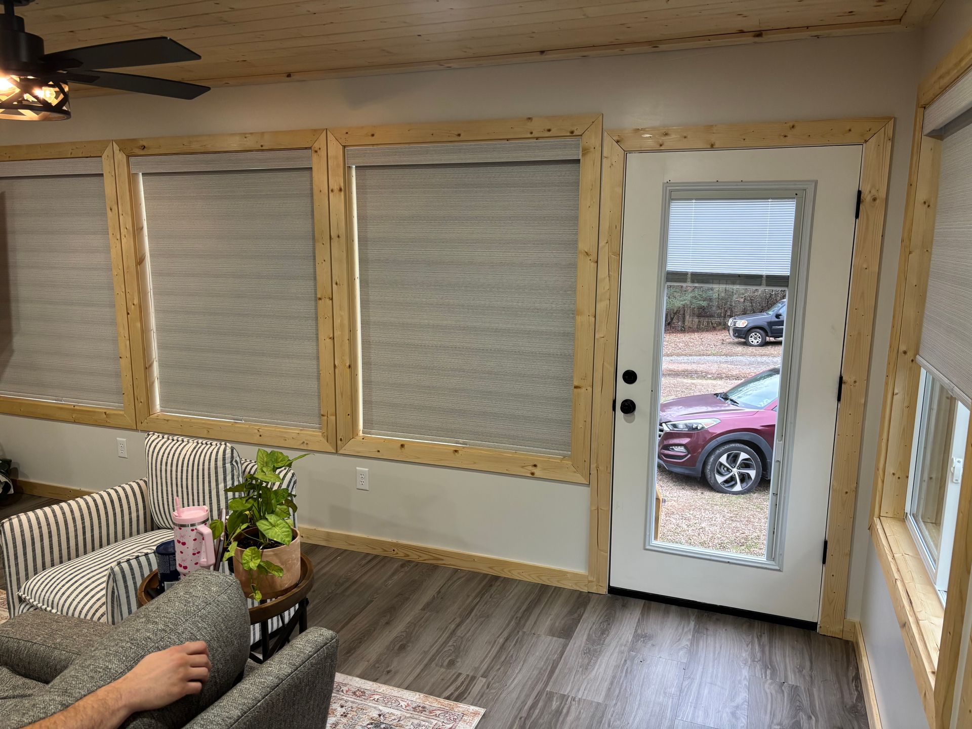 Small room with wood framing, closed blinds, a glass door, and a couch by the window.