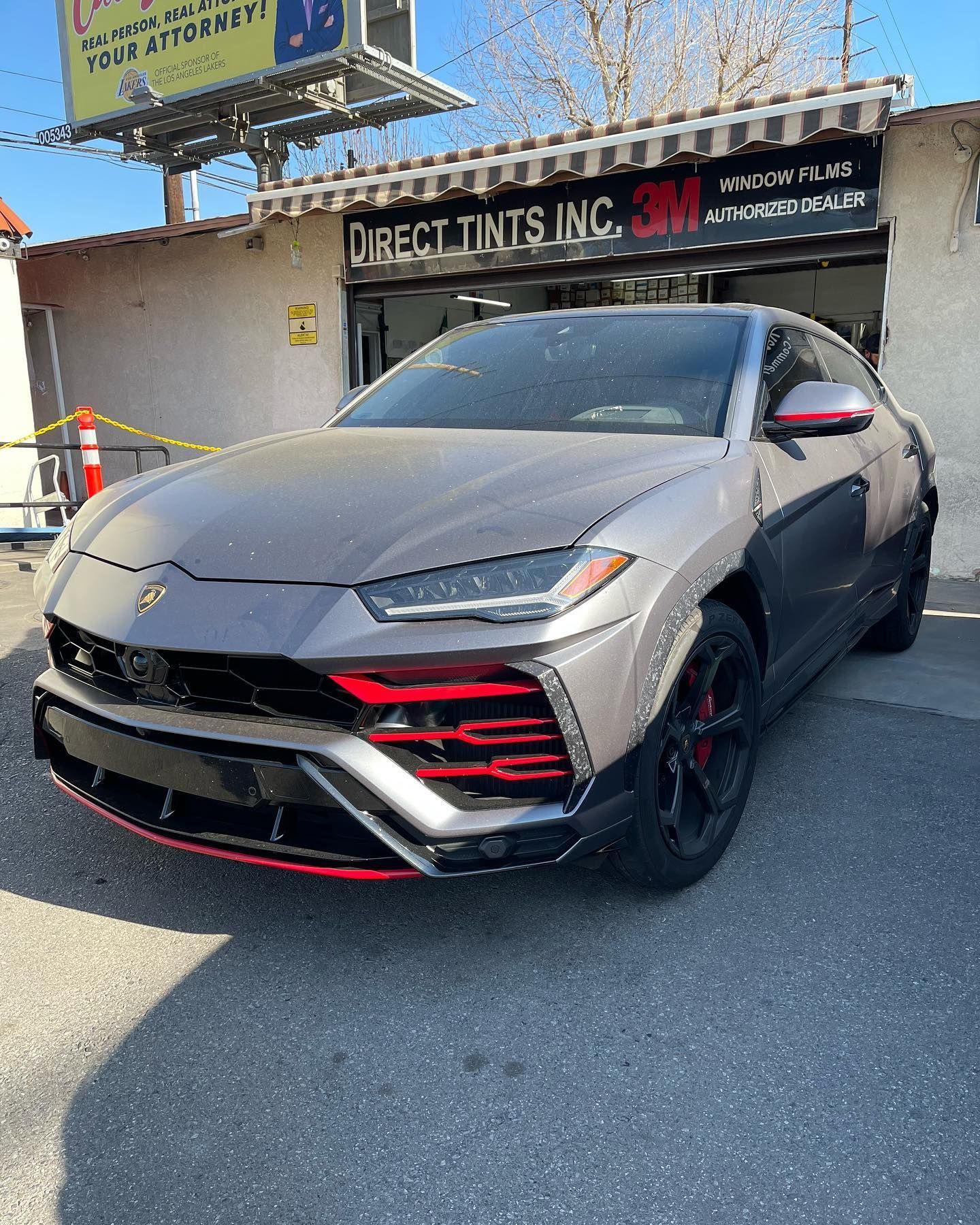 Gray Lamborghini Urus parked in front of Direct Tints Inc. Red accents on front bumper.