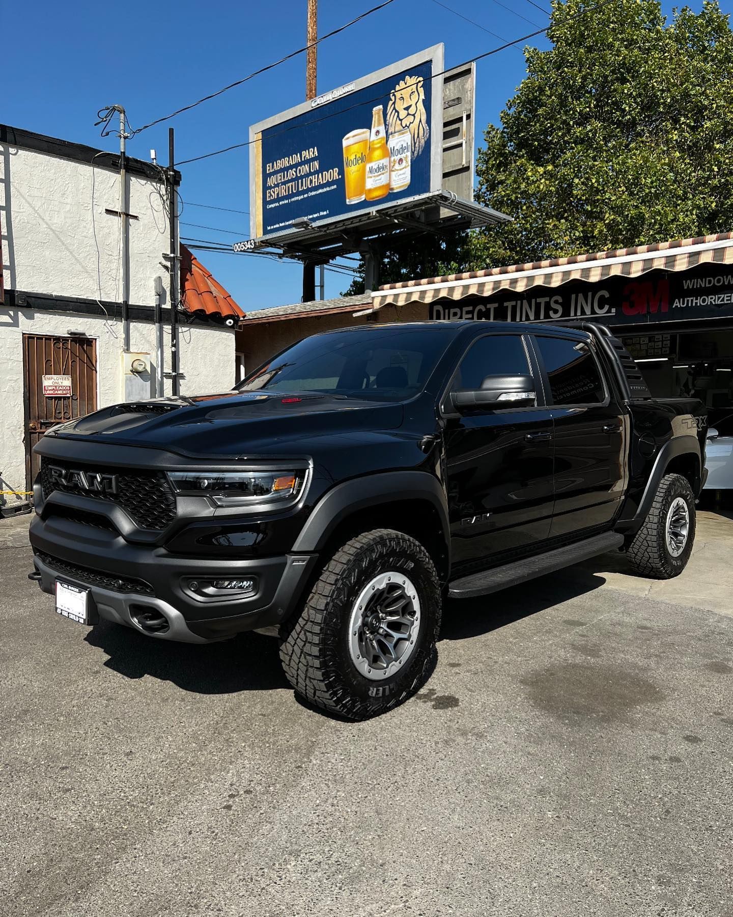 Black RAM TRX truck parked in front of a building with a billboard.