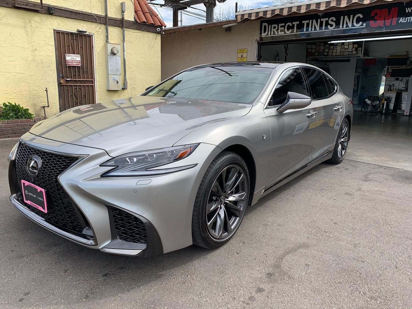Silver Lexus sedan with tinted windows parked outside a tint shop.