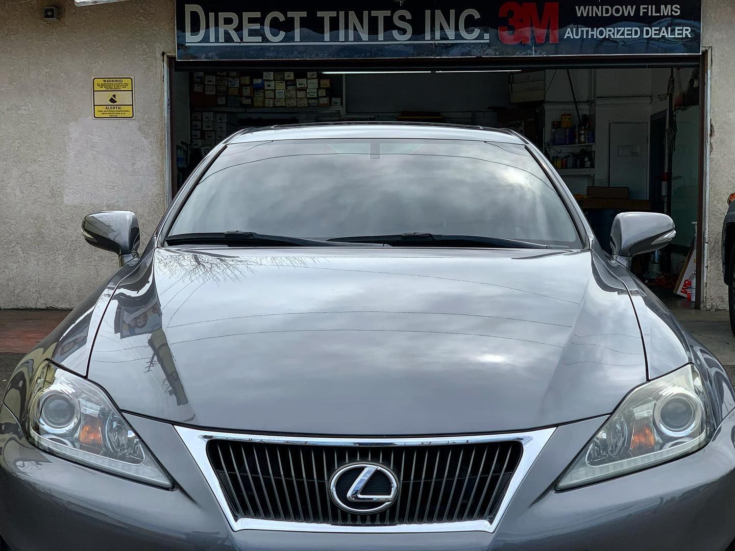 Gray Lexus with tinted windows in front of a 