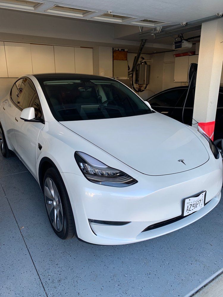 A white Tesla Model Y parked in a residential garage.