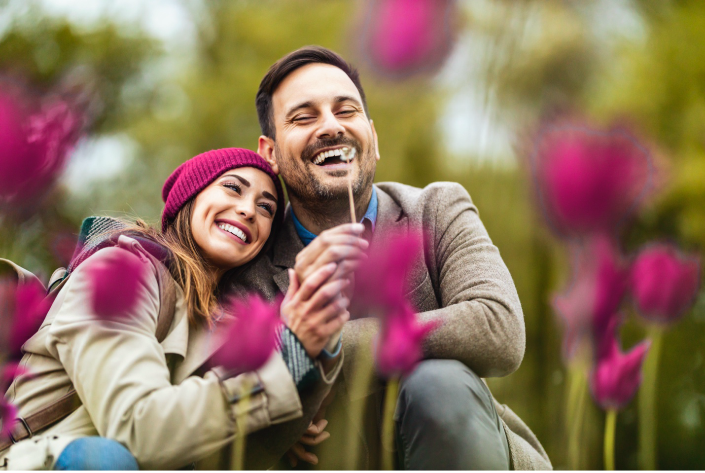 A man and a woman are sitting in a field of purple flowers.