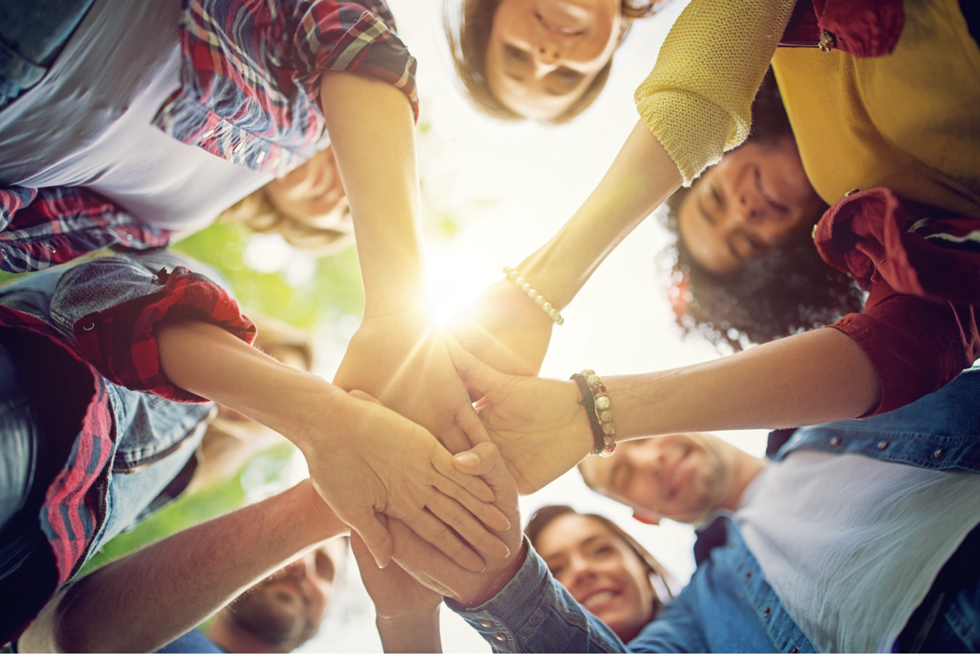 A group of people are putting their hands together in a circle.
