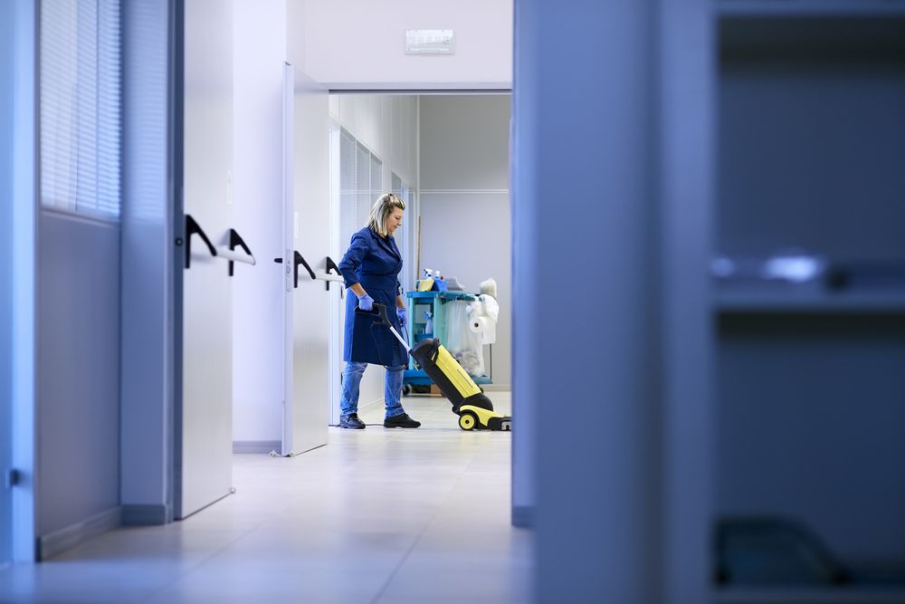 A Woman is Cleaning the Floor of a Building With a Mop — Cleaning for Good in Palm Beach, QLD