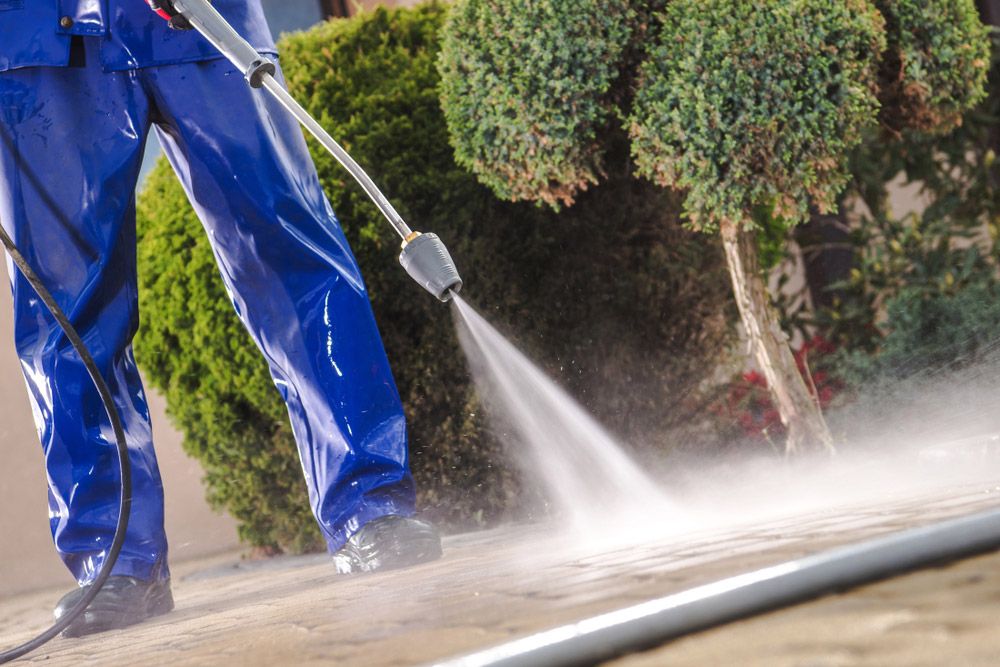 A Man is Using a High Pressure Washer to Clean a Sidewalk — Cleaning for Good in Byron Bay, NSW