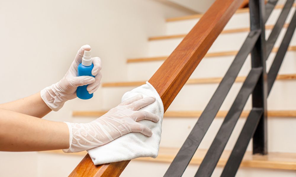 A Person is Cleaning a Wooden Railing With a Cloth and Spray — Cleaning for Good in Lennox Head, NSW