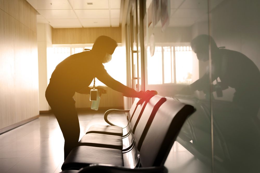 A Man is Cleaning a Waiting Room With a Spray Bottle — Cleaning for Good in Gold Coast, QLD