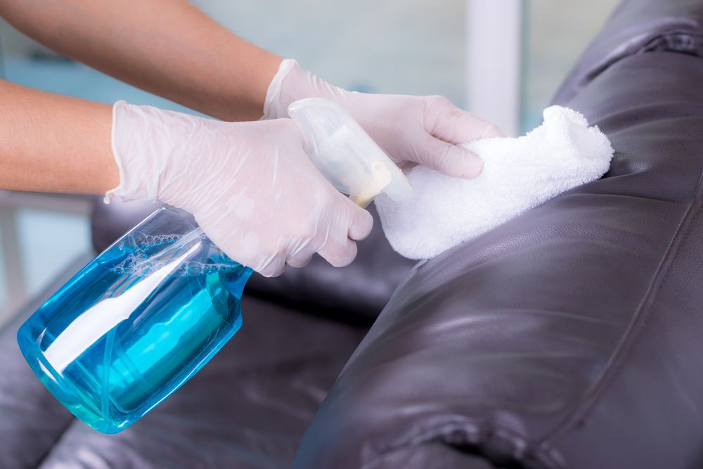 A Person is Cleaning a Leather Couch With a Spray Bottle — Cleaning for Good in Ocean Shores, NSW