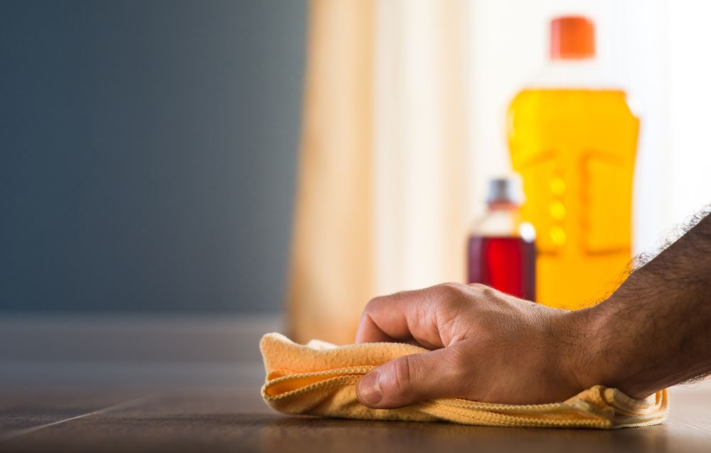 A Person is Cleaning a Wooden Table With a Cloth — Cleaning for Good in Currumbin, QLD