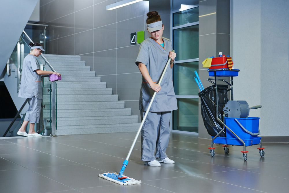 A Woman is Cleaning the Floor With a Mop in an Office Building — Cleaning for Good in Currumbin, QLD