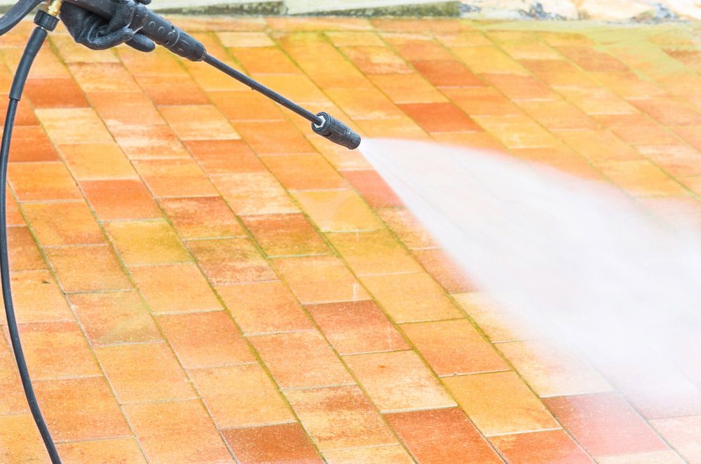 A Person is Using a High Pressure Washer to Clean a Brick Floor — Cleaning for Good in Brunswick Heads, NSW