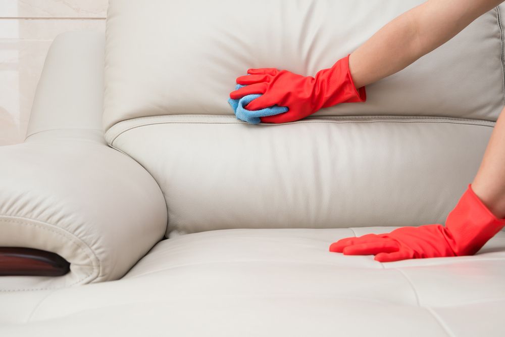 A Person Wearing Red Gloves is Cleaning a White Leather Couch — Cleaning for Good in Bangalow, NSW