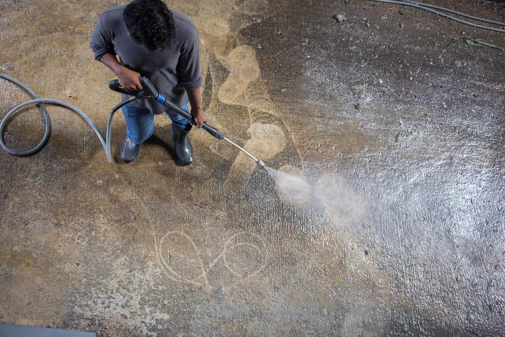 A Person is Cleaning a Wooden Fence With a High Pressure Washer — Cleaning for Good in Alstonville, NSW