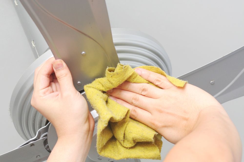 A Person is Cleaning a Ceiling Fan With a Towel — Cleaning for Good in Bangalow, NSW