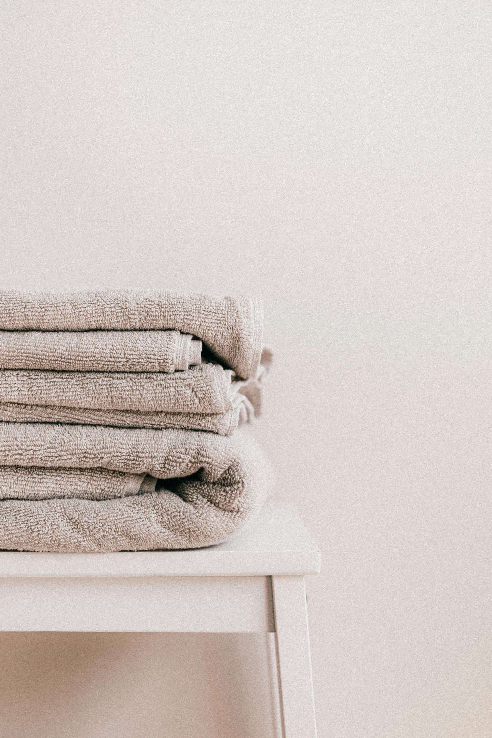 A pile of towels folded on a stool— Cleaning for Good in Byron Bay, NSW