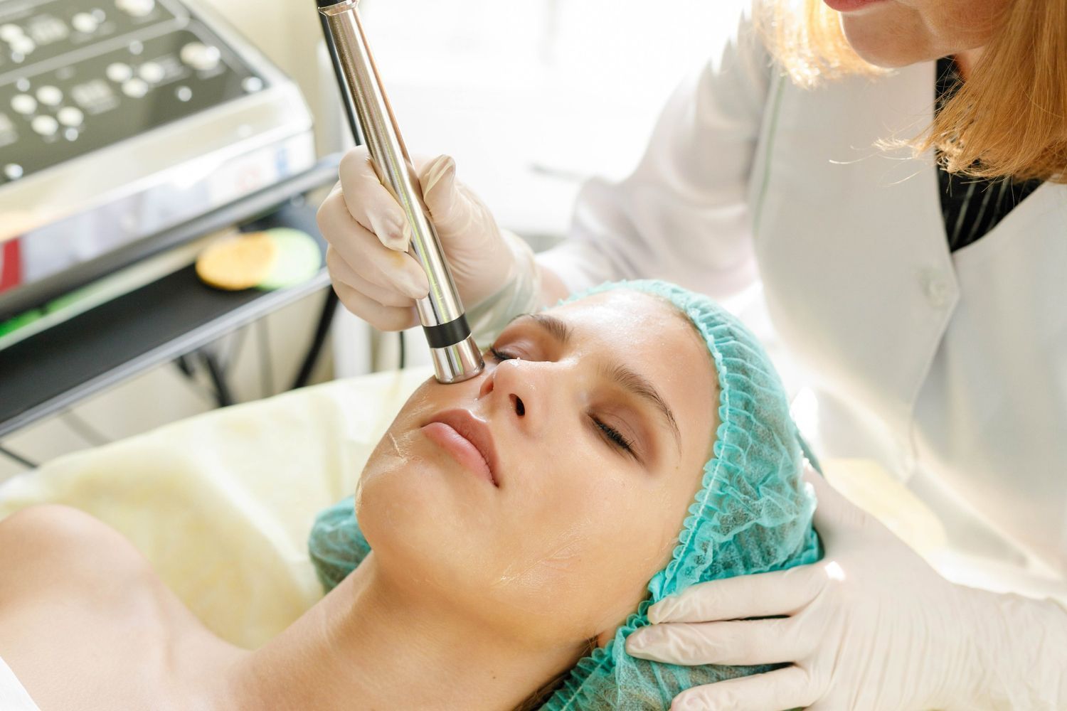 Facial treatment: A woman's face being treated with a device, by a gloved person in a clinical setting.