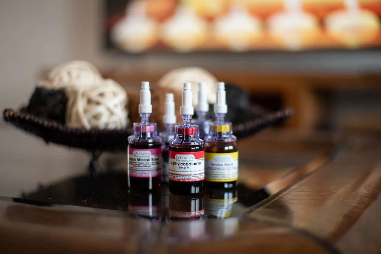 Vials with colored liquids on a reflective surface, with decorative balls in the background.