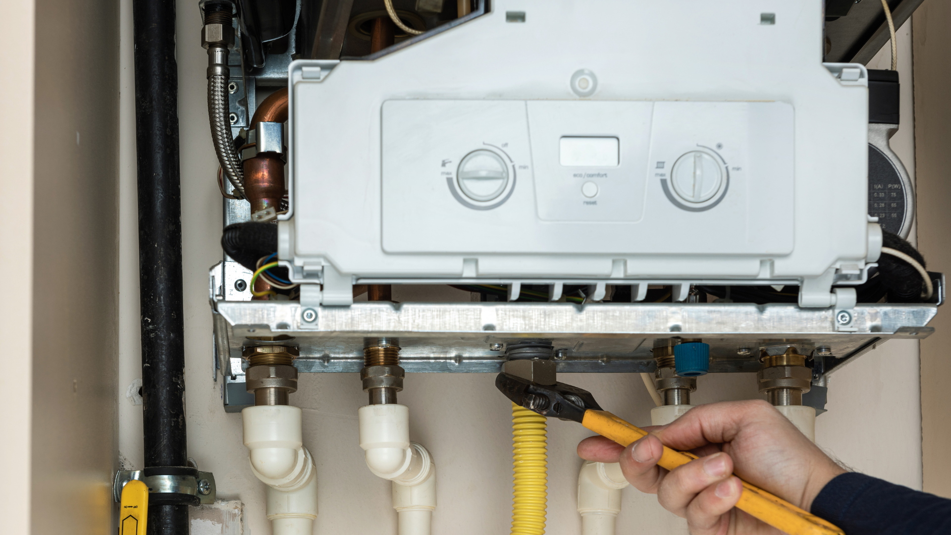 Two wall-mounted water heaters with gray pipes in a clean utility room