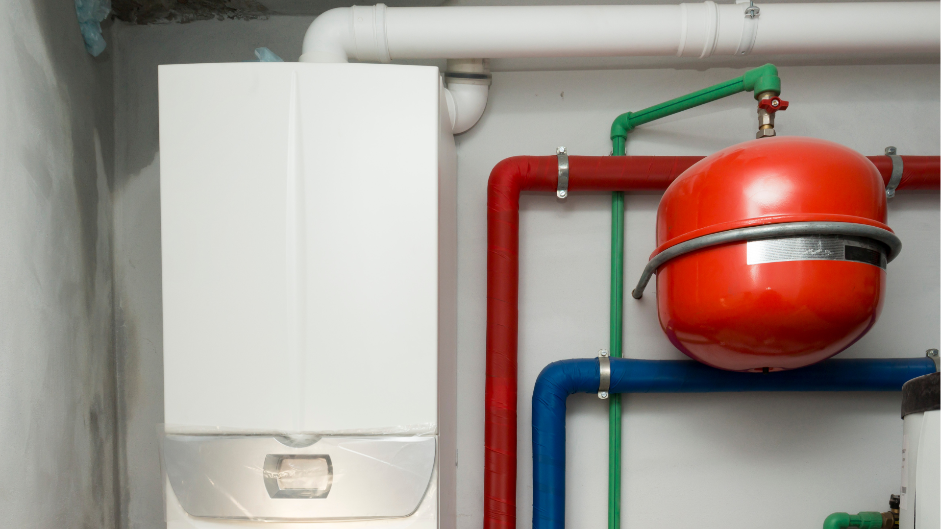 Two black wall-mounted boilers with copper pipes in a utility room