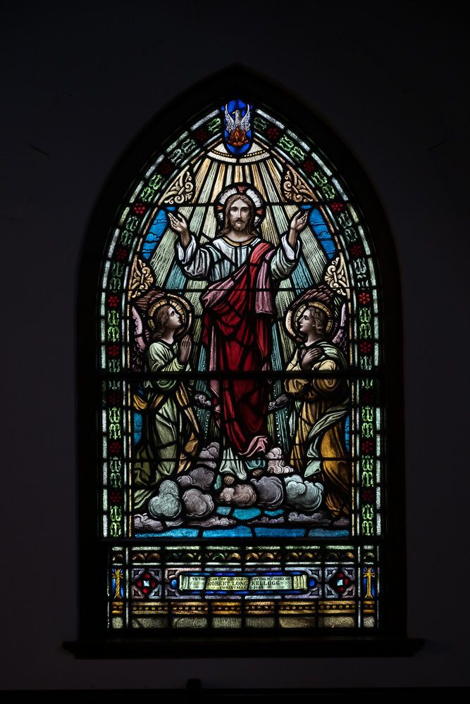 A stained glass window of jesus surrounded by angels in a church.