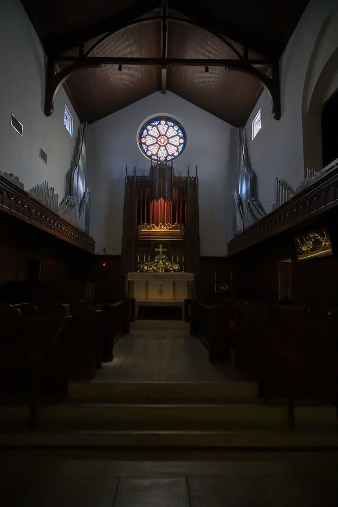 The inside of a church with a stained glass window and altar.