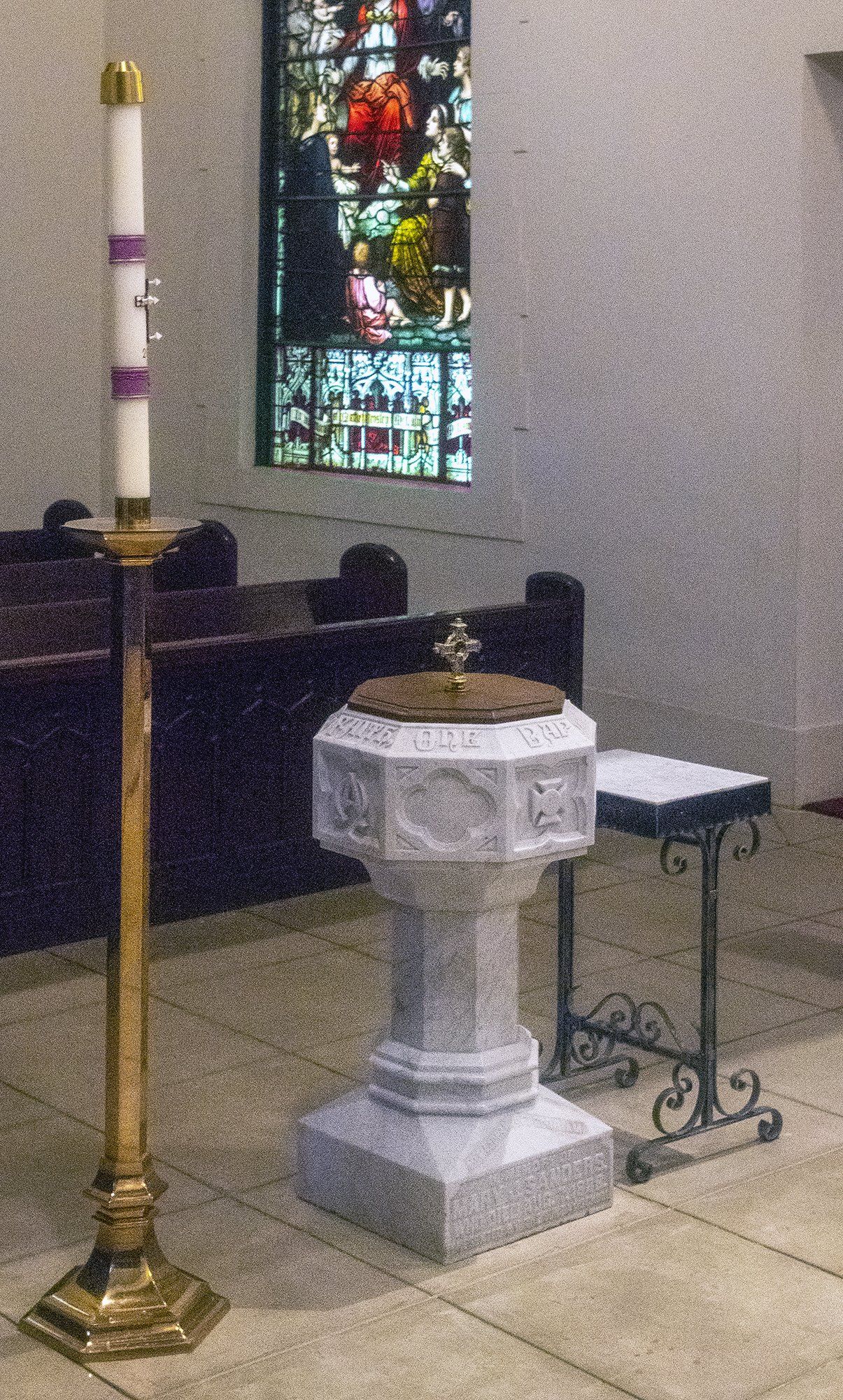 A church with a stained glass window and a baptismal font.