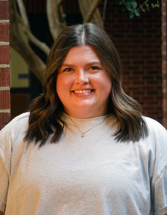 A woman wearing glasses and a striped shirt is smiling for the camera.