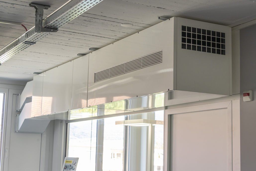 Weiße Klimaanlage, montiert an der Decke über einem Fenster.