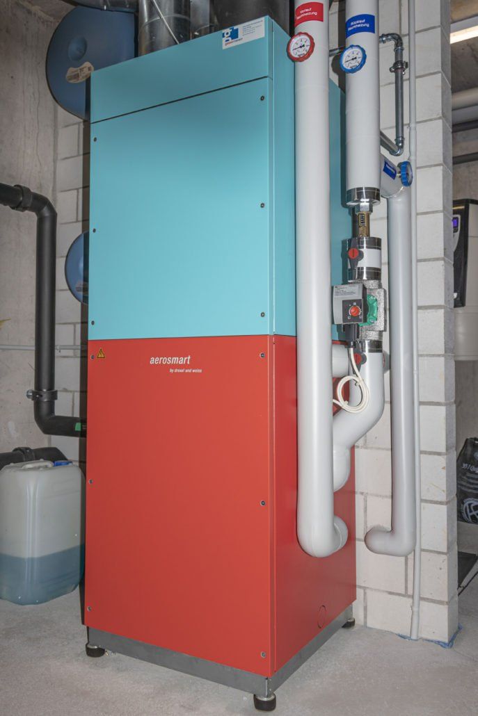 Industrieheizgerät in Blau und Rot mit weißen Rohren in einem Hauswirtschaftsraum.