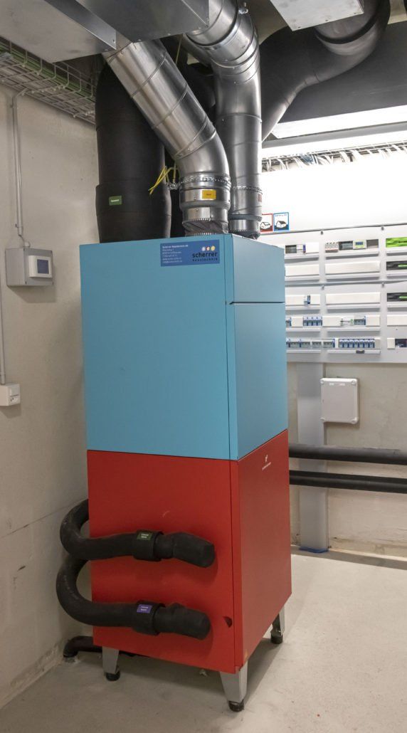 Industrielle Klimaanlage in Blau und Rot mit schwarzen Rohren, in einem Technikraum.