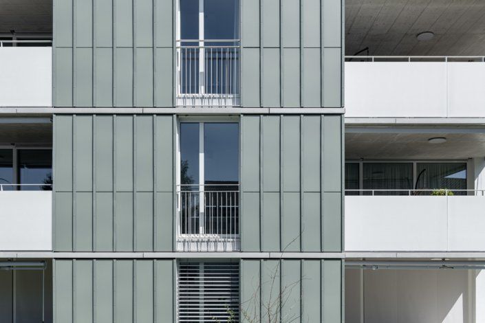Moderne Wohnhausfassade mit Balkonen und grauer Verkleidung.