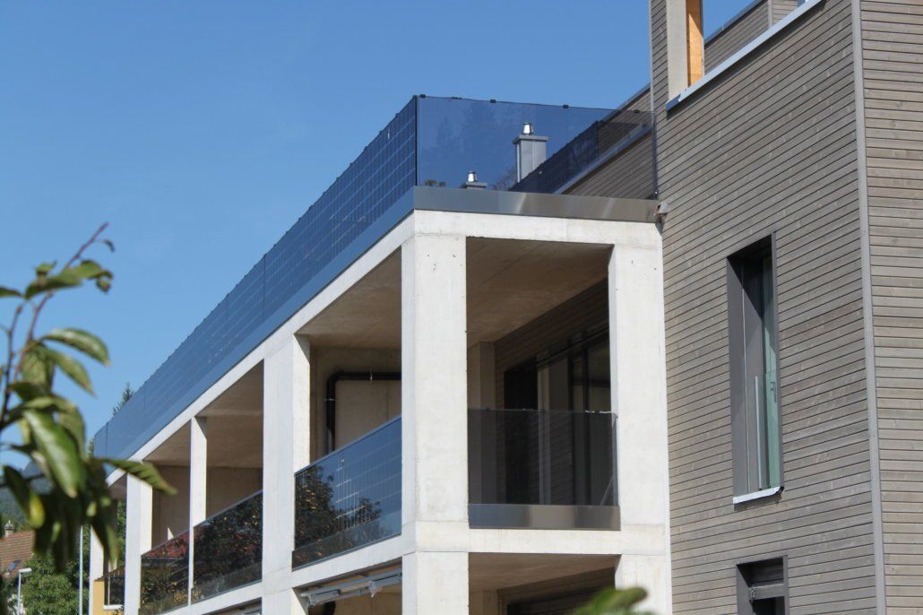 Modernes Gebäude mit blauem Dach, Betonpfeilern und Glasbalkonen.