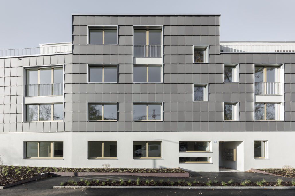 Grau-weißes mehrstöckiges Gebäude mit gemusterter Fassade und zahlreichen Fenstern.