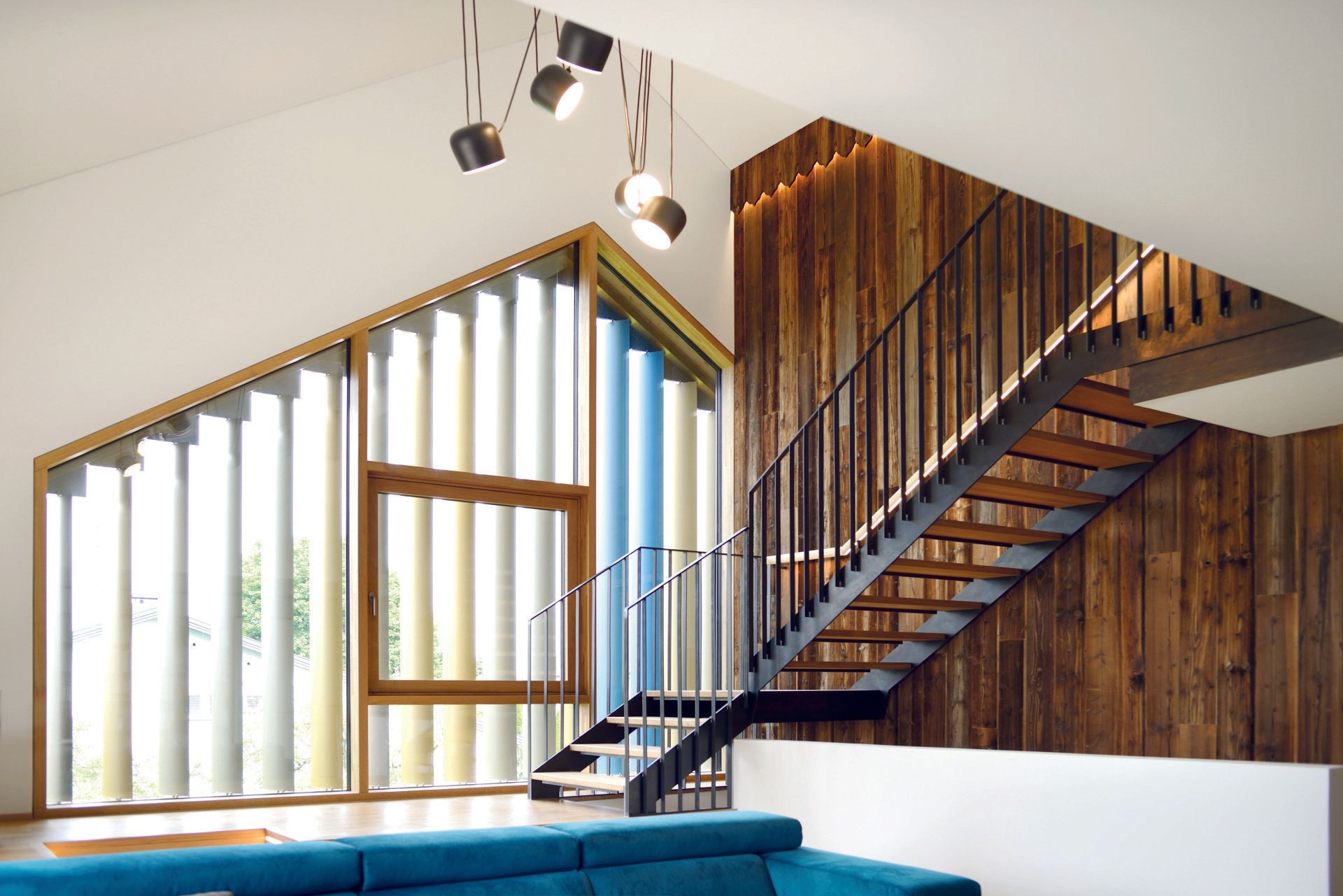 Modernes Interieur mit Treppe, Fenster mit Vertikaljalousien und Holzwand. Blaues Sofa im Vordergrund.