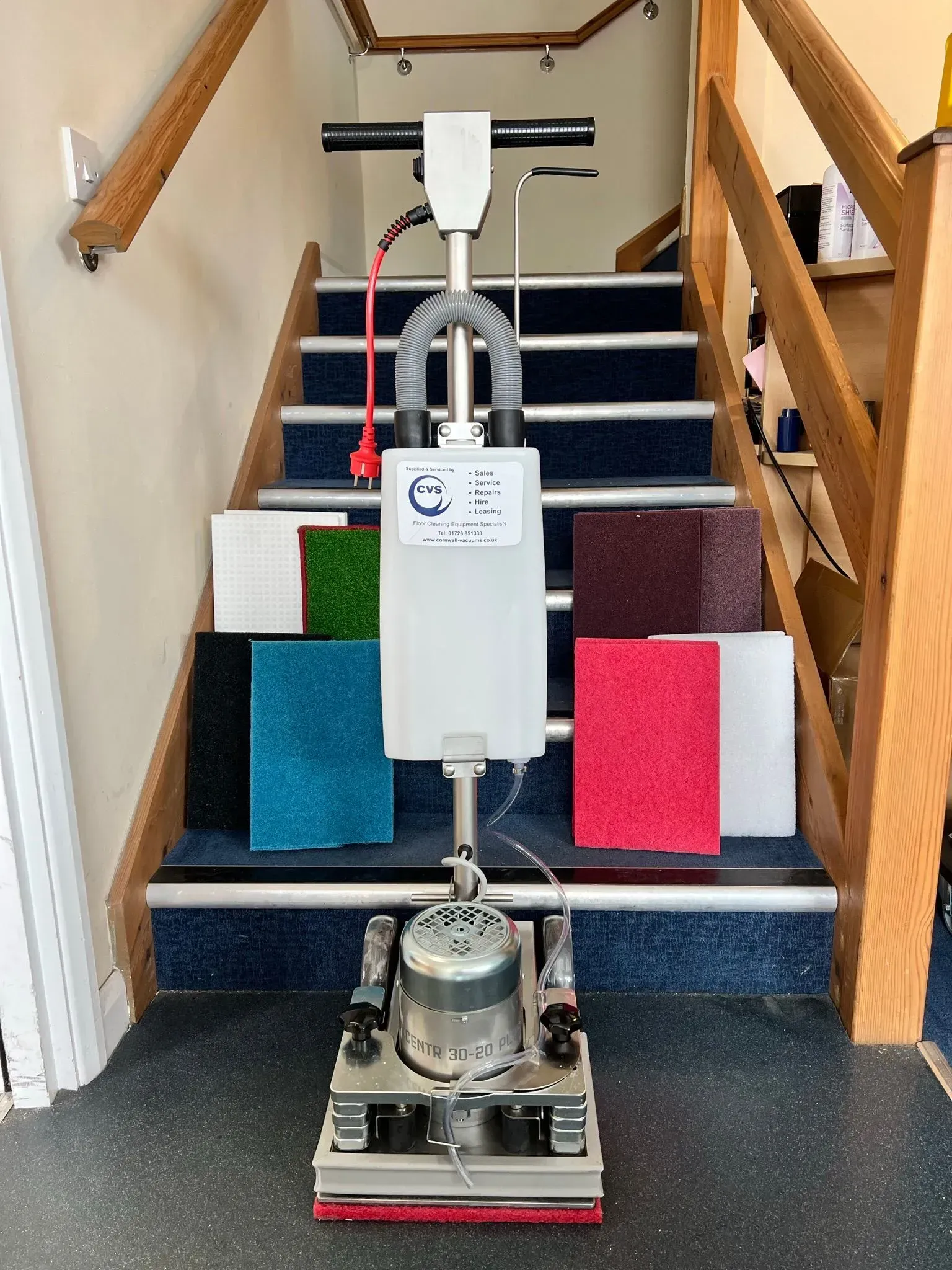 Floor cleaning machine on staircase, with colorful cleaning pads.