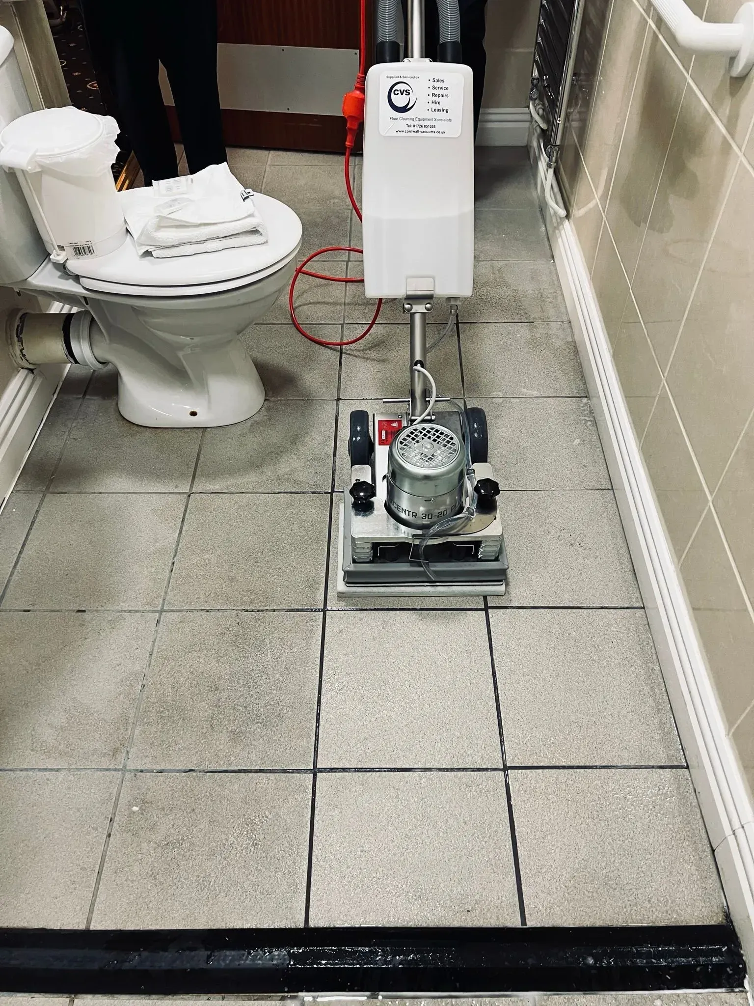 Floor cleaning machine on staircase, with colorful cleaning pads.