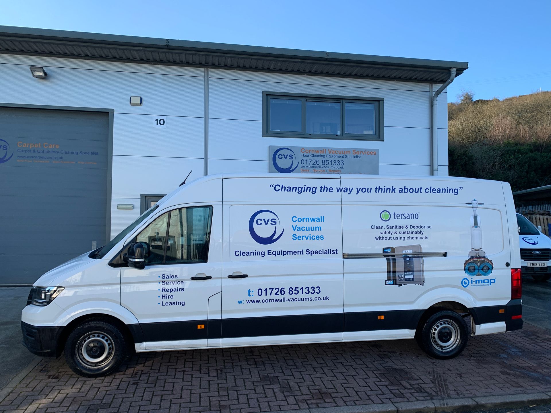 White van with company logo parked outside a building.